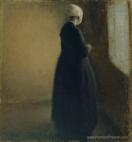 Une vieille femme debout près d'une fenêtre